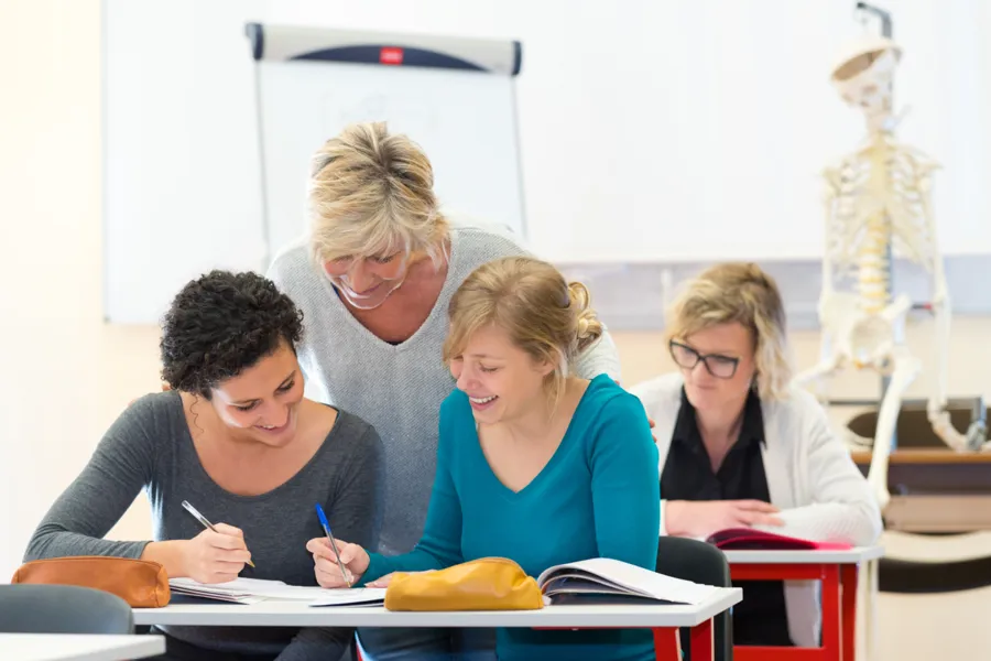 En gruppe mennesker som sitter ved skrivebord og skriver på papir