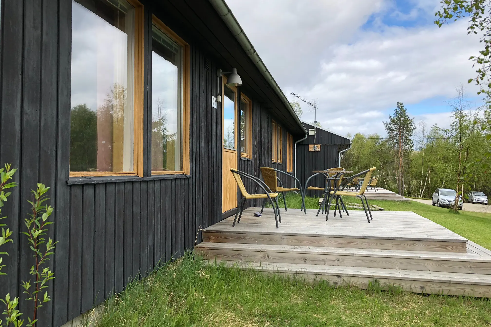 Et tredekk med stoler og et bord på det ved siden av et hus